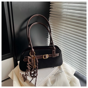 Detail shot of black suede shoulder bag with brown leather straps and gold metal key charm