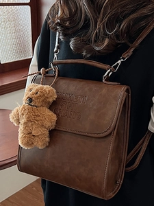 Vintage brown shoulder bag with embossed letters and a cute plush bear charm decoration
