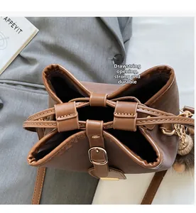 Detail of dark brown bucket bag showing drawstring closure and stylish fuzzy ball charm