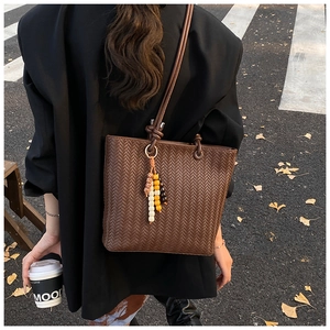 Close-up of a deep brown woven texture tote bag with stylish colorful bead charm