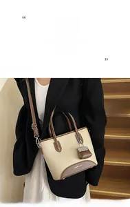 Detailed shot of beige canvas handbag with brown leather trim and metal hardware accents