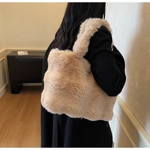 Vue latérale du grand sac cabas en fausse fourrure beige porté sur un manteau noir