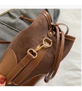 Detail of glossy brown leather bucket bag showing polished gold-tone metal hardware