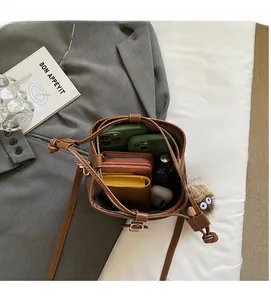Interior storage capacity of the brown bucket bag showing phones and wallet details