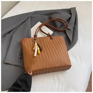 Brown woven tote bag detail with colorful beaded tassel on a grey blazer jacket