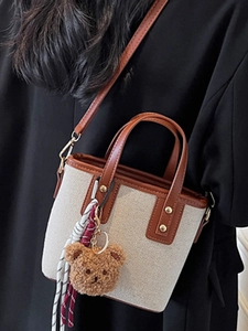 Chic canvas bucket bag with brown leather trim and cute bear charm for women