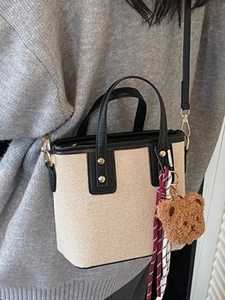 Minimalist canvas bucket bag with black leather trim and adjustable strap worn by model