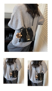 Detail view of black leather bucket bag with leopard print texture and bear charm