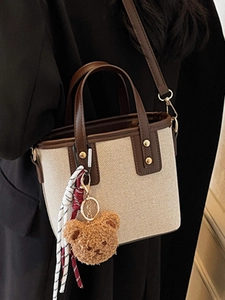 Canvas and leather bucket bag with brown trim and cute bear charm shown with model