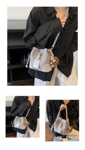 Close-up of light grey bucket bag featuring gold buckle and brown plush charm