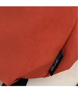 Detail of the high-quality orange twill fabric and brand label on a stylish backpack
