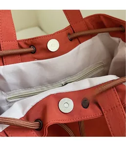 Detail of magnetic silver buckle and woven drawstring inside the brick red backpack