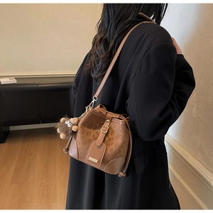 Close-up of retro brown bucket bag with plush charm and reinforced corners detail