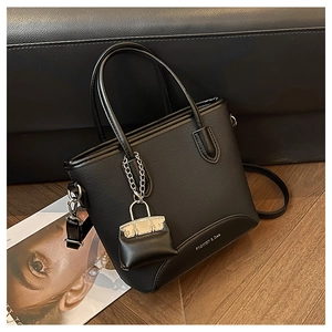 Detail of black PU leather bucket bag with silver hardware and mini bag charm