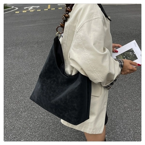 Detail of a large black tote bag featuring unique dark brown wooden bead shoulder straps