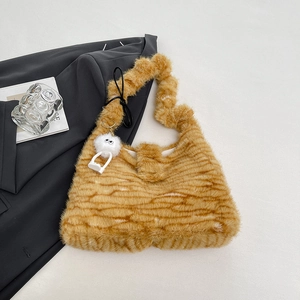 Detail der Plüsch-Tragetasche mit gelbem Tigermuster und weißem Monster-Schlüsselanhänger