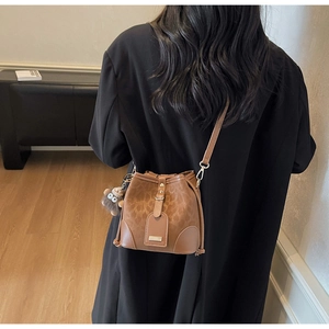 Brown leopard print bucket bag with bear charm worn with a black wool coat