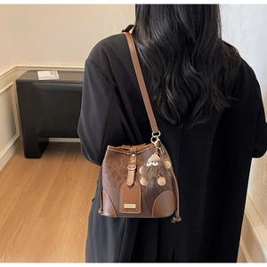 Detail of vintage brown bucket bag with monogram pattern and plush monster charm