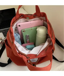Detail view of spacious orange backpack interior showing laptop and daily essentials