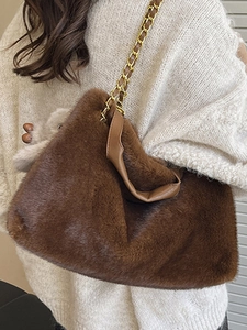 Sac bandoulière en fausse fourrure marron avec chaîne dorée sur fond de pull blanc