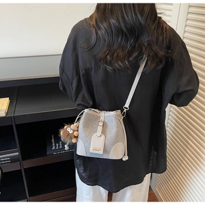 Detail of grey bucket bag with baroque textures and a cute plush lion charm accessory