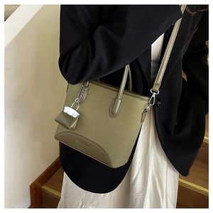 Close-up of olive green canvas tote bag showing leather strap and brand detail on stairs