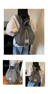 Detail view of dark grey canvas backpack with drawstring closure and brand label