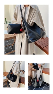 Detail of black faux leather hobo bag featuring large capacity and a red pompom charm