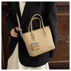 Detail of camel bucket bag with metal chain mini-bag charm and fashion text print