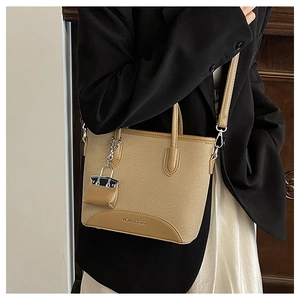 Detail view of khaki canvas and leather bucket bag with fashion charm on a model