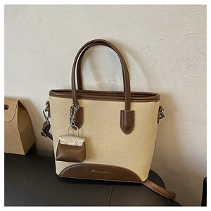 Close-up of retro mini canvas tote bag with brown leather trim and mini bag charm