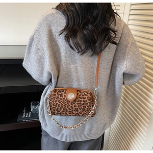 Détail du sac léopard avec rabat en cuir marron et bandoulière chaîne porté par un mannequin