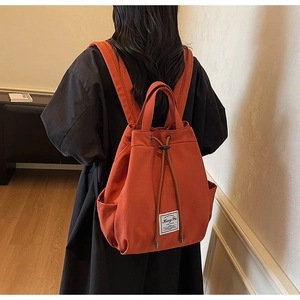 Detail of caramel canvas backpack with drawstring closure and side pockets for daily travel