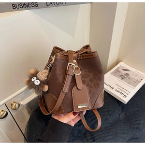 Detailed view of a brown bucket bag with leopard embossed texture and plush charm
