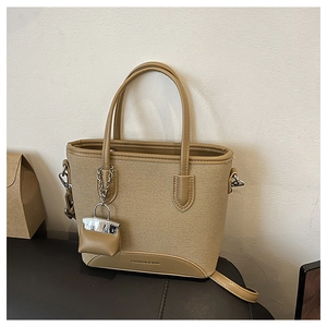 Detailed macro of khaki canvas bucket bag with leather trim and mini purse charm