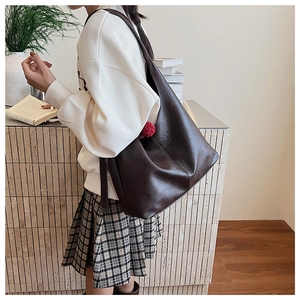 Close-up of deep brown leather bucket bag with wide strap and minimalist design