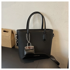 Detail of black leather bucket bag with a mini charm and silver metal chain accessory
