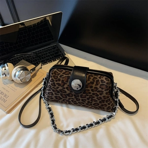 Détail du sac léopard avec bandoulière chaîne argentée et badge métallique décoratif