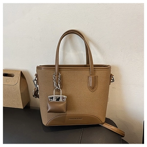 Detail view of brown canvas tote with leather trim, mini pouch and fashion lettering