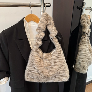 Detail einer Plüschtasche mit Leopardenmuster und gerafftem Henkel neben einem Blazer