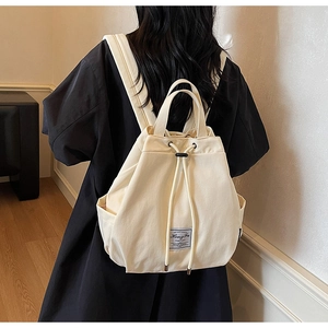 Detailed back view of a beige canvas drawstring backpack with vintage brand patch