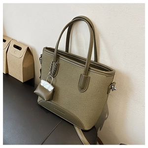 Detail of olive green canvas tote bag showing the texture and mini pouch accessory