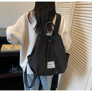 Detail of minimalist black canvas drawstring backpack featuring side pockets and top handle