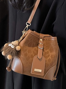 Brown leather bucket crossbody bag with drawstring and cute monster plush pendant charm