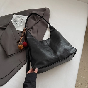 Detail of black large hobo bag with textured faux leather and plush charm accessory