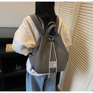 Detailed side view of grey canvas drawstring backpack with minimalist brand label