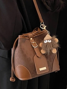 Chic brown suede bucket bag with contrast leather trim and cute plush charm detail