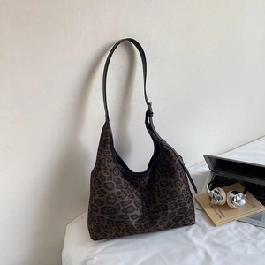 Leopard print hobo bag next to laptop and headphones in a stylish lifestyle setting