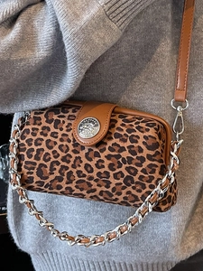Sac à main léopard tendance avec boucle argentée et bandoulières en cuir sur un pull gris
