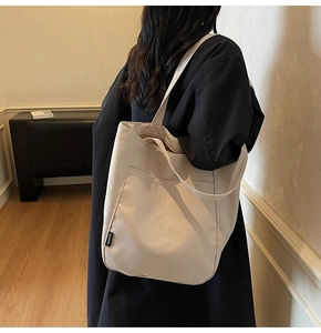 Detail of the outer pocket and fashion label on a beige waterproof nylon tote bag